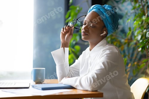 Preview: Overworked african woman freelancer suffeing from headache, cafe interior