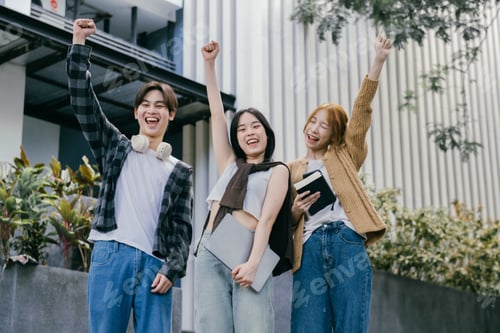 Preview: Three cheerful asian students raising their arms in celebration of their academic achievement, expre