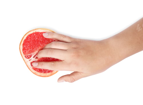 Preview: Young woman touching half of grapefruit on white background, top view. Sex concept