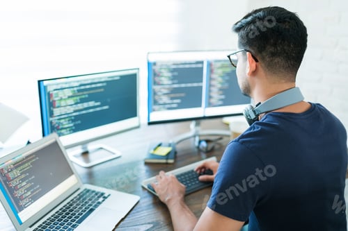 Preview: Hispanic Male Programmer Coding At Desk