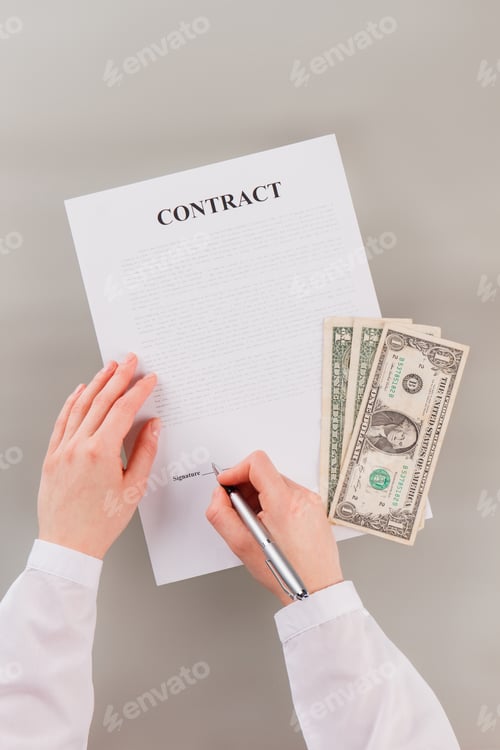 Preview: Business woman signing contract with money on the table.