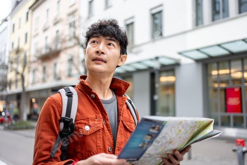 Preview: Asian young man backpacker traveler looking at map to find destination.