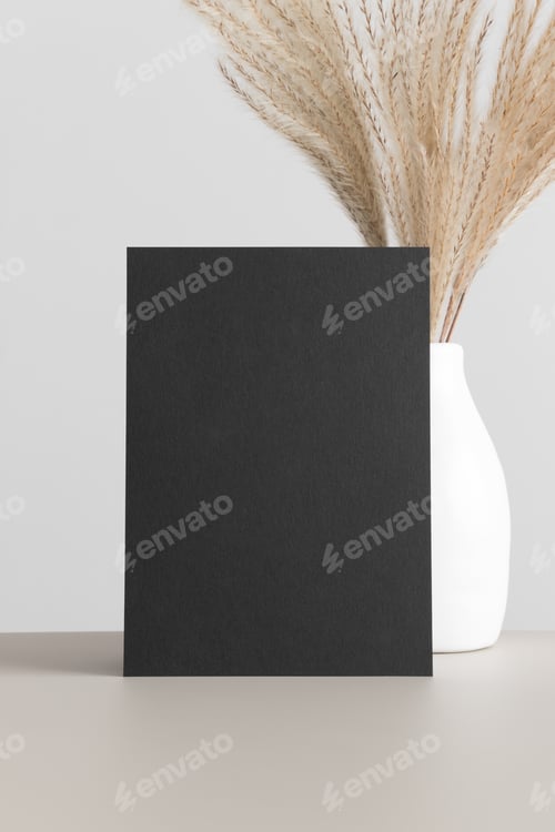Preview: Black invitation card mockup with a reed pampas on the beige table. 5x7 ratio, similar to A6, A5.