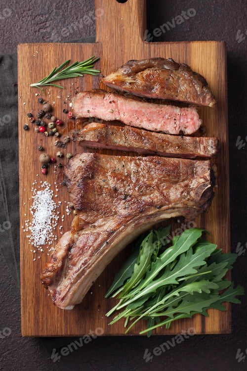 Preview: Grilled cowboy beef steak, herbs and spices on a rustic wooden background.