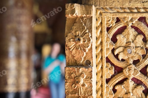 Preview: Macro close up view of a golden decorative door entrance to a Buddhist temple with blurred visitors