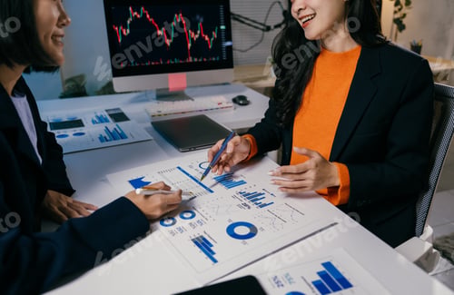 Preview: Two businesswomen are discussing financial charts and graphs, analyzing data and working together on