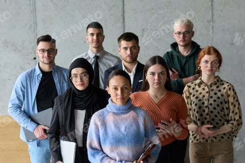 Preview: A diverse and determined team of business professionals stands confidently in an office, ready to