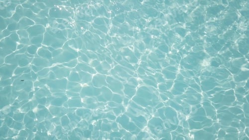 Preview: Water in swimming pool rippled water detail background. Water in swimming pool with sun reflection