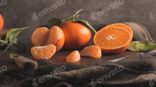 Preview: Tangerines and orange slices arranged on a dark wooden board