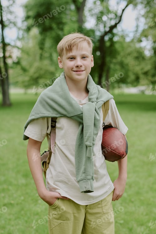 Preview: Caucasian Boy Smiling While Holding Football Outdoors in Park
