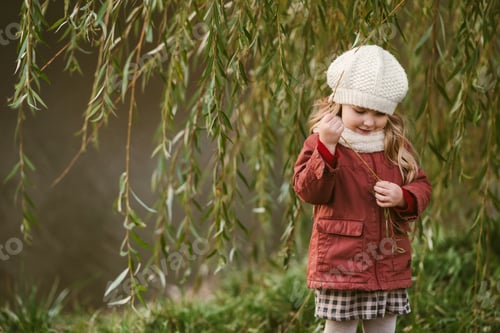 Preview: A cute girl is standing next to a willow tree