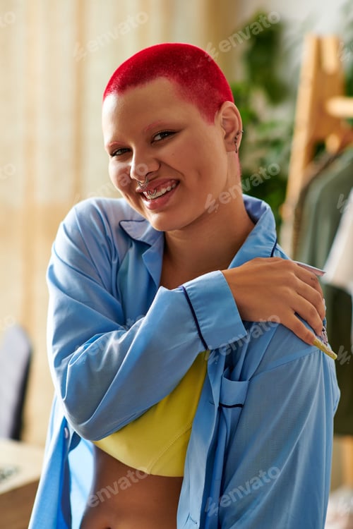 Preview: Young woman with vibrant red hair enjoys a relaxed moment at home in cozy attire