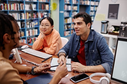 Preview: Multiethnic group of young people studying together in college library
