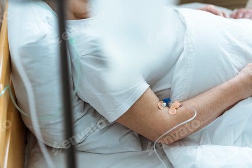 Preview: partial view of sick woman lying on bed during intravenous therapy in clinic