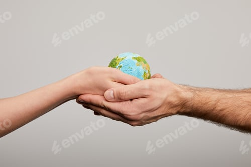 Preview: man and woman holding planet model on grey background, earth day concept
