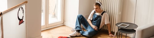 Preview: Young white man in headphones working on craft rug at home