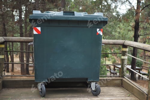 Vista previa: Metal green garbage can with wheels in countryside