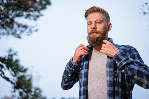 Preview: Young caucasian bearded man in plaid shirt traveling alone in autumn forest