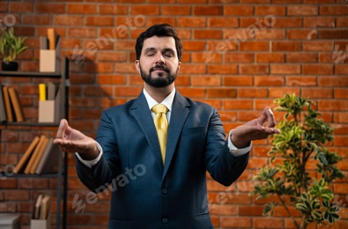 Preview: CEO in suit doing namaste gesture peacefully in cozy modern office with closed eyes