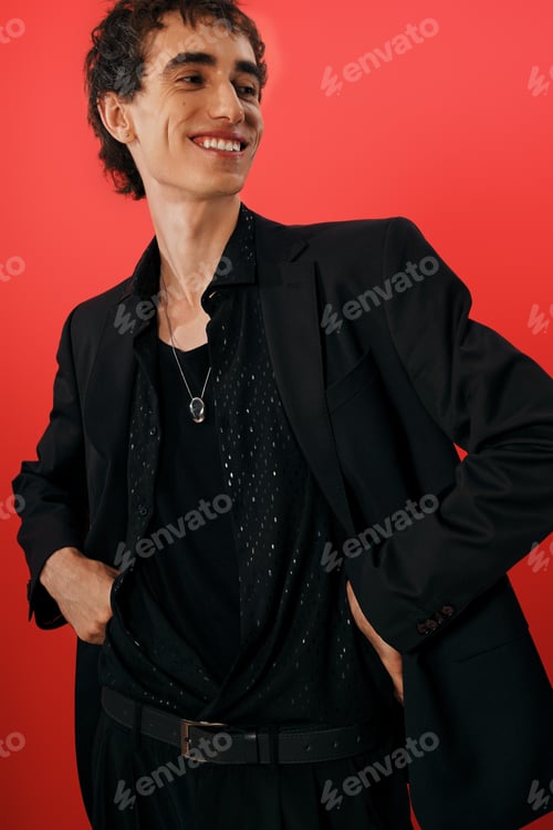 Preview: Elegant man showcasing stylish fashion against a vibrant red background in a cheerful pose