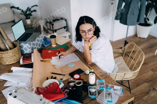 Preview: Pensive female designer drawing sketch at workplace