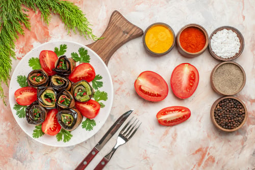 Preview: top view tasty eggplant rolls with tomatoes and different seasonings on the light background dish
