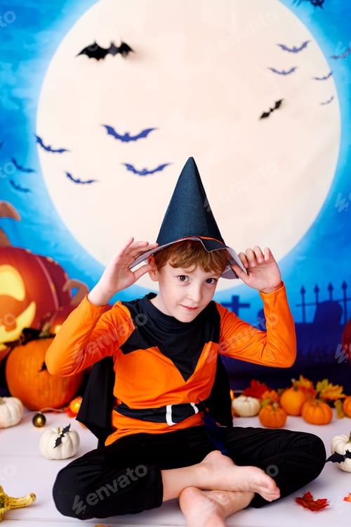 Preview: Halloween concept. Smiling kid with pumpkins on halloween spooky background