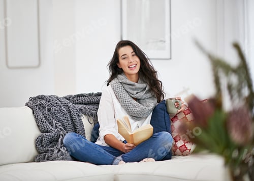 Preview: My weekend is all booked. Shot of a young woman reading a book while sitting in the living room.