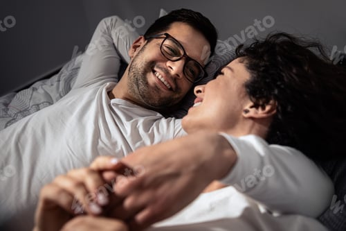 Preview: Smiling couple laying in bed and cuddles in the bedroom.