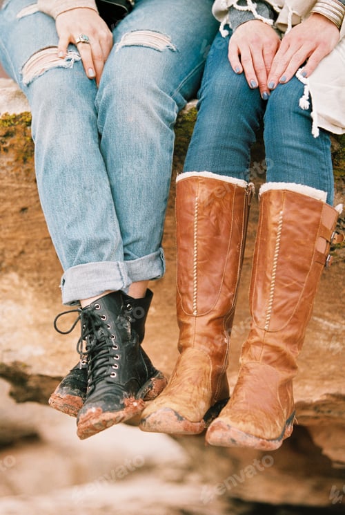 Preview: Close up of two women wearing leather boots sitting on a rock