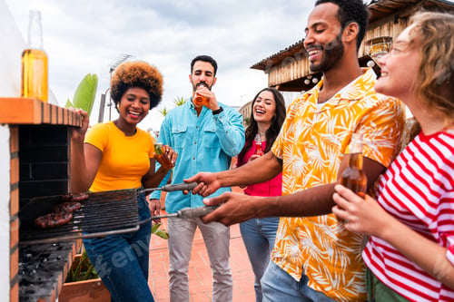 Preview: Multiethnic group of friends having dinner barbecue party on rooftop at home