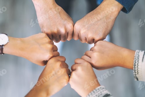 Preview: Top view image of people putting their fisted hands in circle together