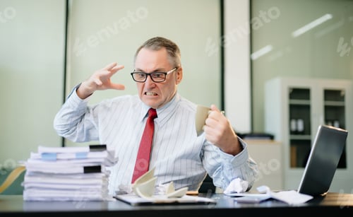 Preview: Angry and irritated Mature Businessman sitting in the office of laptop with his keyboard tired