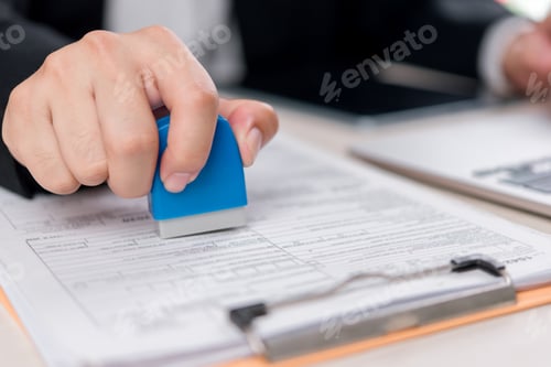 Preview: A corporate worker applying a stamp to an official document, process of document approval