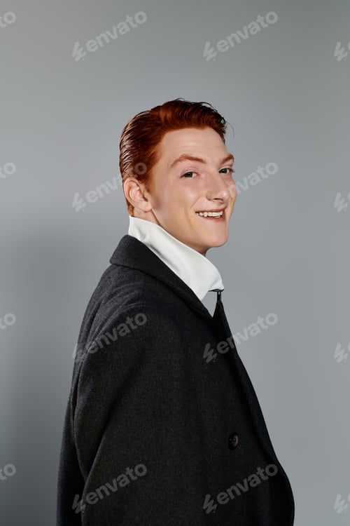 Preview: Young, stylish man with red hair in a trendy winter coat against a grey background