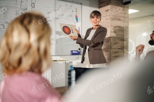 Preview: Marketing manager presenting business strategy to colleagues in meeting room