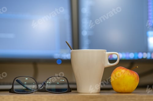 Preview: White cup of coffee or tea, glasses and a red apple on blurred background of personal computer