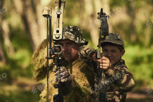 Preview: Portrait of a father and son in camouflage hunting with bows and arrows in the woods