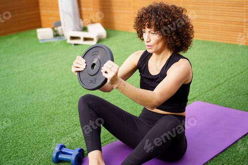 Preview: A woman is performing strength training while using a weight plate on an exercise mat