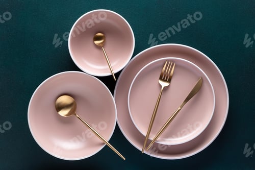 Preview: Crockery and golden cutlery on a dark green background, table top view, above. Flat lay design.