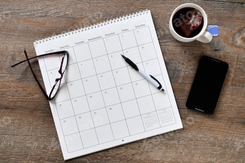 Preview: Overhead flat lay view of calendar, phone, pen scheduling work personal appointments - blank no year