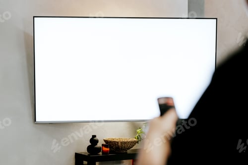 Preview: Hand holding remote control pointing to TV. Person watching smart television