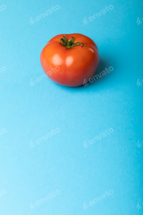 Preview: Close-up of fresh red tomato over copy space against blue background