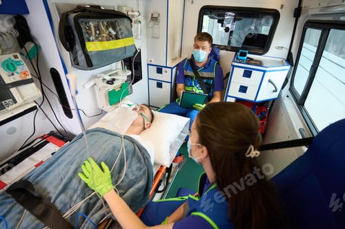 Preview: Doctors of mobile team transport patient under drip in ambulance
