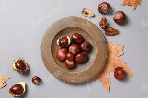 Preview: Brown, fresh chestnut fruits in a bowl with leaves