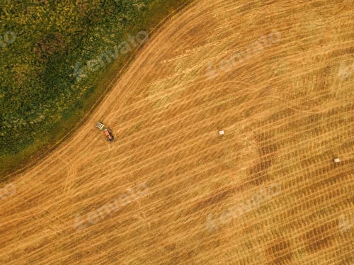 Preview: Aerial view of tractor making hay bale rolls in field