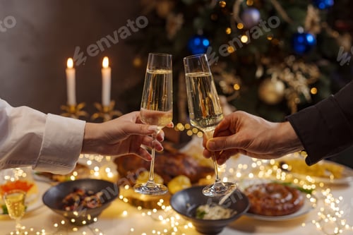 Visualização: mãos com taças de champanhe em close-up no fundo de uma mesa festiva de Natal