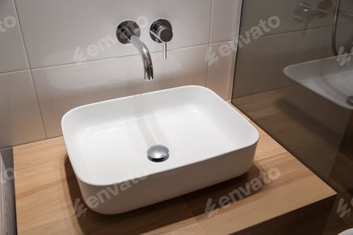 Preview: Close up of sink and faucet on wooden shelf in white bathroom interior