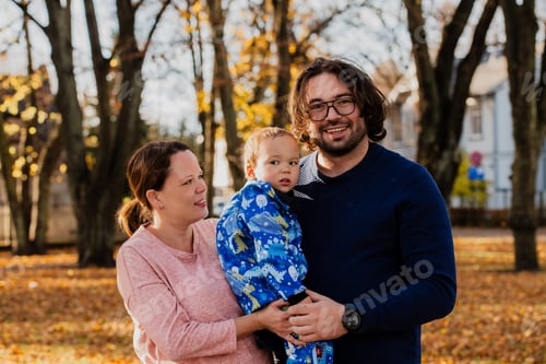 Preview: On a sunny autumn day in the park, a mother and father lovingly embrace their young son, sharing