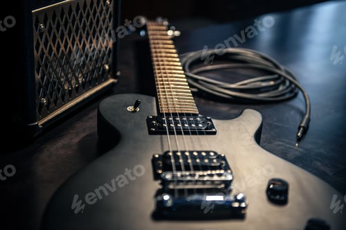 Preview: Close-up, black electric guitar on a dark background.